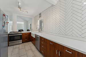 Kitchen with light countertops, a sink, modern cabinets, and stainless steel appliances