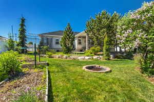 View of green lawn with a garden and an outdoor fire pit