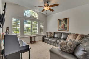 Carpeted living room with ceiling fan, baseboards, and crown molding