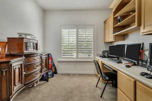 Office space featuring carpet floors, built in desk, and baseboards