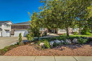 Obstructed view of property featuring concrete driveway, a garage, brick siding, and fence