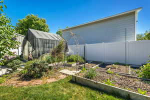 Fenced backyard featuring an exterior structure, a garden, and an outdoor structure