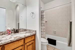 Full bath with tile patterned flooring, toilet, vanity, and shower / tub combo with curtain