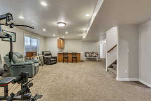 Living area featuring recessed lighting, light colored carpet, a textured ceiling, stairs, and baseboards