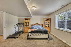 Bedroom with a textured ceiling, light carpet, and baseboards