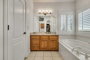 Full bathroom featuring a bath, tile patterned floors, vanity, and a walk in closet