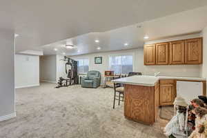 Kitchen featuring open floor plan, recessed lighting, light colored carpet, a kitchen breakfast bar, and a sink