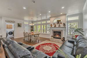 Living room featuring crown molding, washer and clothes dryer, a textured ceiling, wood finished floors, and baseboards