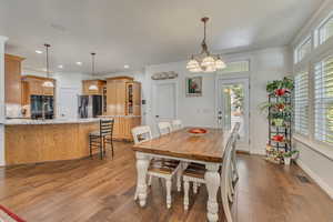 Dining space with plenty of natural light, wood finished floors, crown molding, recessed lighting, and a chandelier