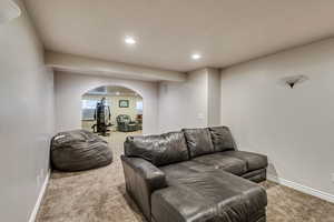 Carpeted living room featuring arched walkways, recessed lighting, and baseboards