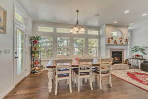 Dining room featuring ornamental molding, a fireplace, wood finished floors, a chandelier, and recessed lighting