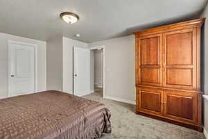 Bedroom featuring light colored carpet, a textured ceiling, and baseboards