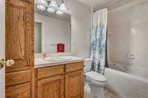 Full bathroom with tile patterned floors, toilet, vanity, and tiled shower / bath combo