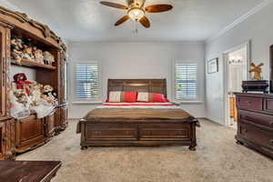 Bedroom with light colored carpet, a textured ceiling, ornamental molding, baseboards, and ensuite bathroom