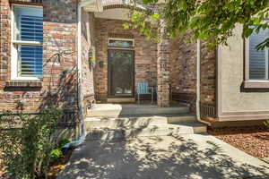 Entrance to property featuring brick siding and covered porch