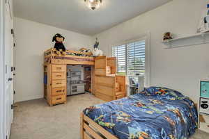 Bedroom featuring light colored carpet, baseboards, and a textured ceiling