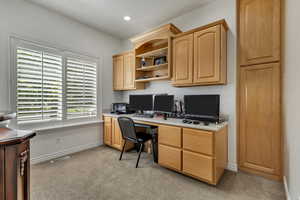 Office space featuring built in desk, light colored carpet, baseboards, and recessed lighting