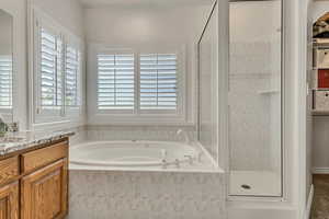 Bathroom featuring a shower stall, a bath, and vanity