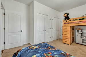 Bedroom featuring light colored carpet and multiple closets
