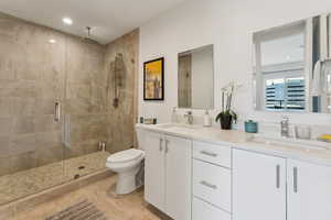 Full bath with a stall shower, double vanity, toilet, and recessed lighting