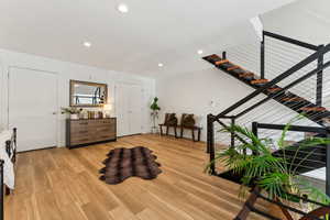 Sitting room with light wood finished floors, recessed lighting, and stairway