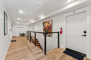 Foyer featuring an AC wall unit, baseboards, light wood-style floors, and recessed lighting