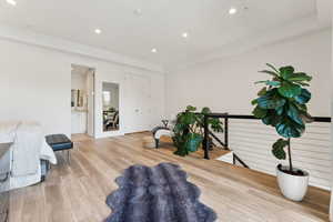 Living area featuring light wood-style flooring, an upstairs landing, and recessed lighting