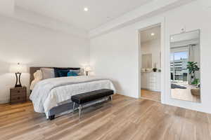 Bedroom featuring light wood-style flooring, recessed lighting, baseboards, and ensuite bath