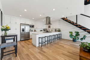 Kitchen featuring stainless steel appliances, island exhaust hood, a peninsula, a kitchen breakfast bar, and recessed lighting