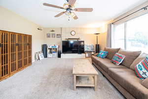 Living room with carpet, ceiling fan, and baseboards