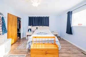 Bedroom featuring wood finished floors, a closet, baseboards, and a ceiling fan