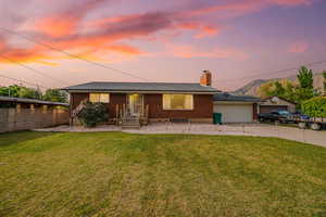 Ranch-style house featuring concrete driveway, brick siding, a chimney, and a mountain view