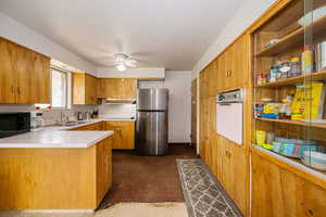Kitchen with freestanding refrigerator, oven, black microwave, a ceiling fan, and a sink
