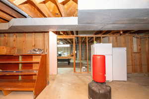 Unfinished basement with freestanding refrigerator