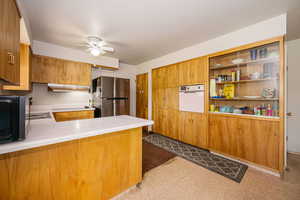 Kitchen with white oven, freestanding refrigerator, under cabinet range hood, ceiling fan, and tile patterned floors
