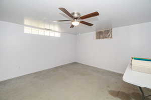 Carpeted empty room featuring ceiling fan and baseboards