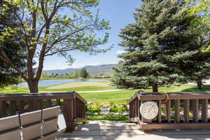 Wooden deck featuring a water and mountain view, golf course view, and a yard