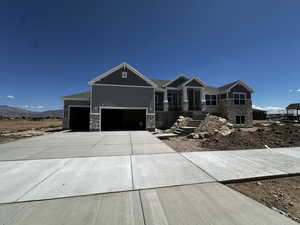 Craftsman-style home featuring board and batten siding, a garage, concrete driveway, stone siding, and a mountain view