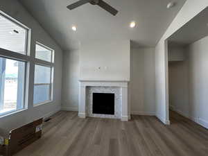 Unfurnished living room with ceiling fan, wood finished floors, a tile fireplace, a textured ceiling, and recessed lighting