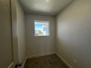 Spare room with dark colored carpet, baseboards, and a textured ceiling