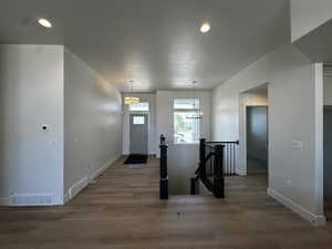 Entryway featuring wood finished floors, baseboards, a textured ceiling, recessed lighting, and a chandelier