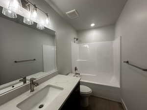 Full bath featuring toilet, wood finished floors, vanity, washtub / shower combination, and recessed lighting