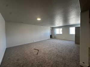 Carpeted empty room featuring baseboards, a textured ceiling, and recessed lighting