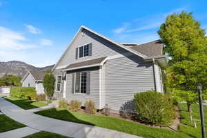 View of side of property with a lawn, roof with shingles, and a mountain view
