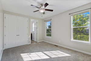 Unfurnished bedroom with carpet, a closet, baseboards, and a ceiling fan