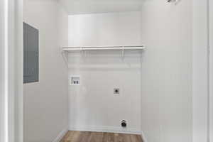 Laundry room featuring electric panel, hookup for an electric dryer, hookup for a washing machine, wood finished floors, and baseboards