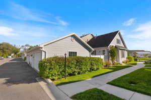 View of property exterior featuring a lawn, driveway, and a garage