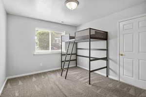 Unfurnished bedroom featuring carpet, baseboards, and a textured ceiling