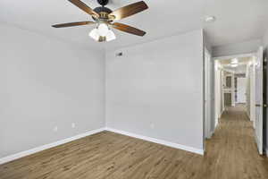 Spare room with light wood-type flooring, baseboards, a ceiling fan, and a smoke detector