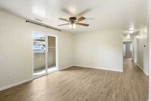 Spare room with ceiling fan, light wood-type flooring, and baseboards